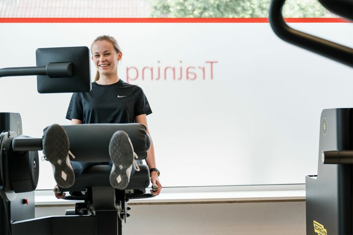 Eine Frau traininert Ihre Beinmuskulatur auf einem Trainingsgerät